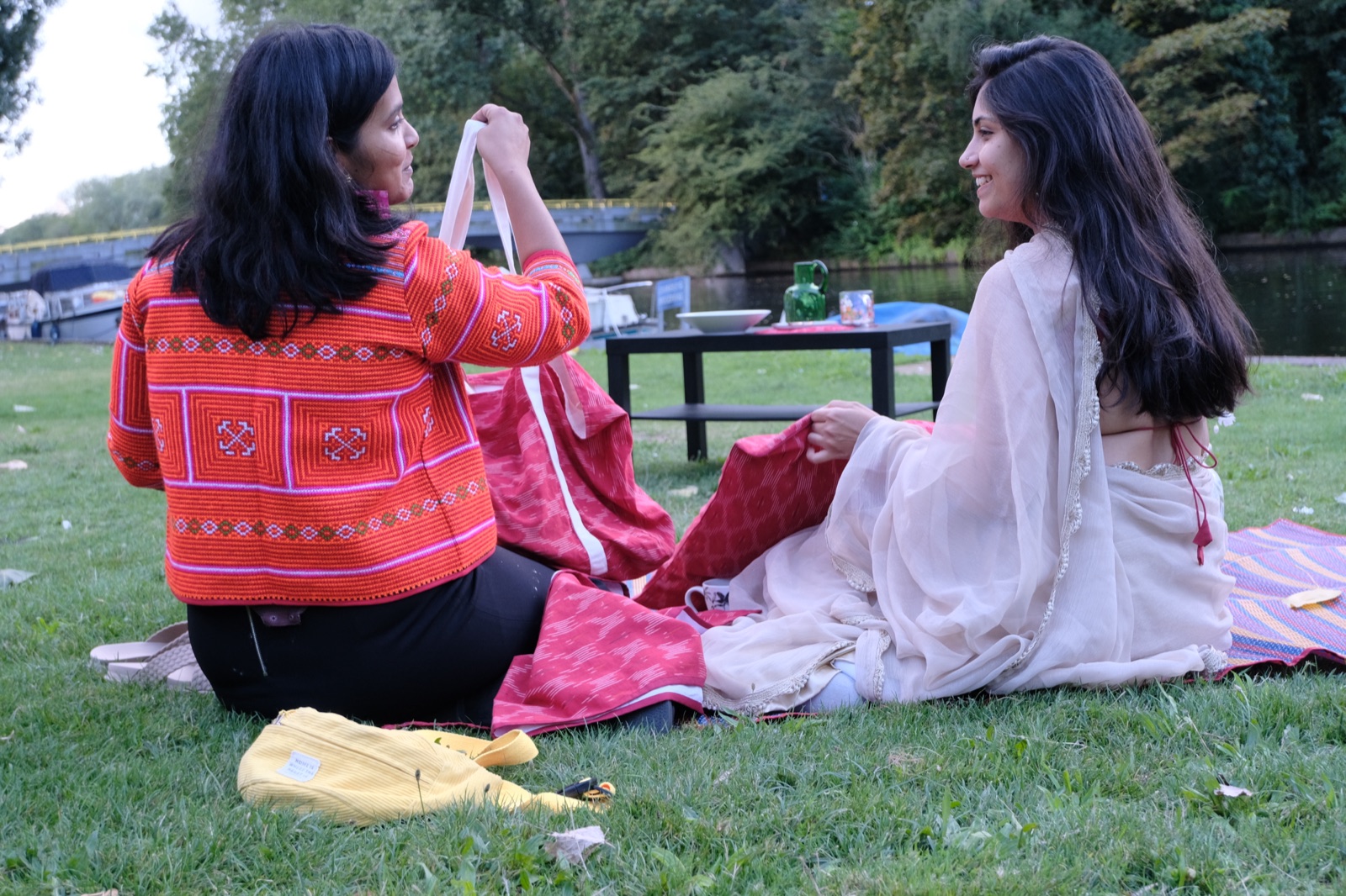 Dimple and Akkriti sharing a picnic by an Amsterdam canal, with Ghar textiles